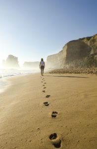 Frau spaziert am Sandstrand